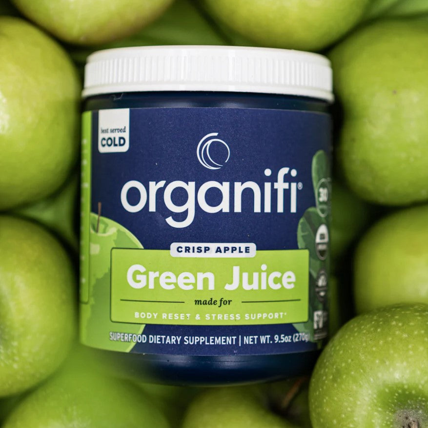 a canister of Organifi Green Juice Crisp Apple laying between apples